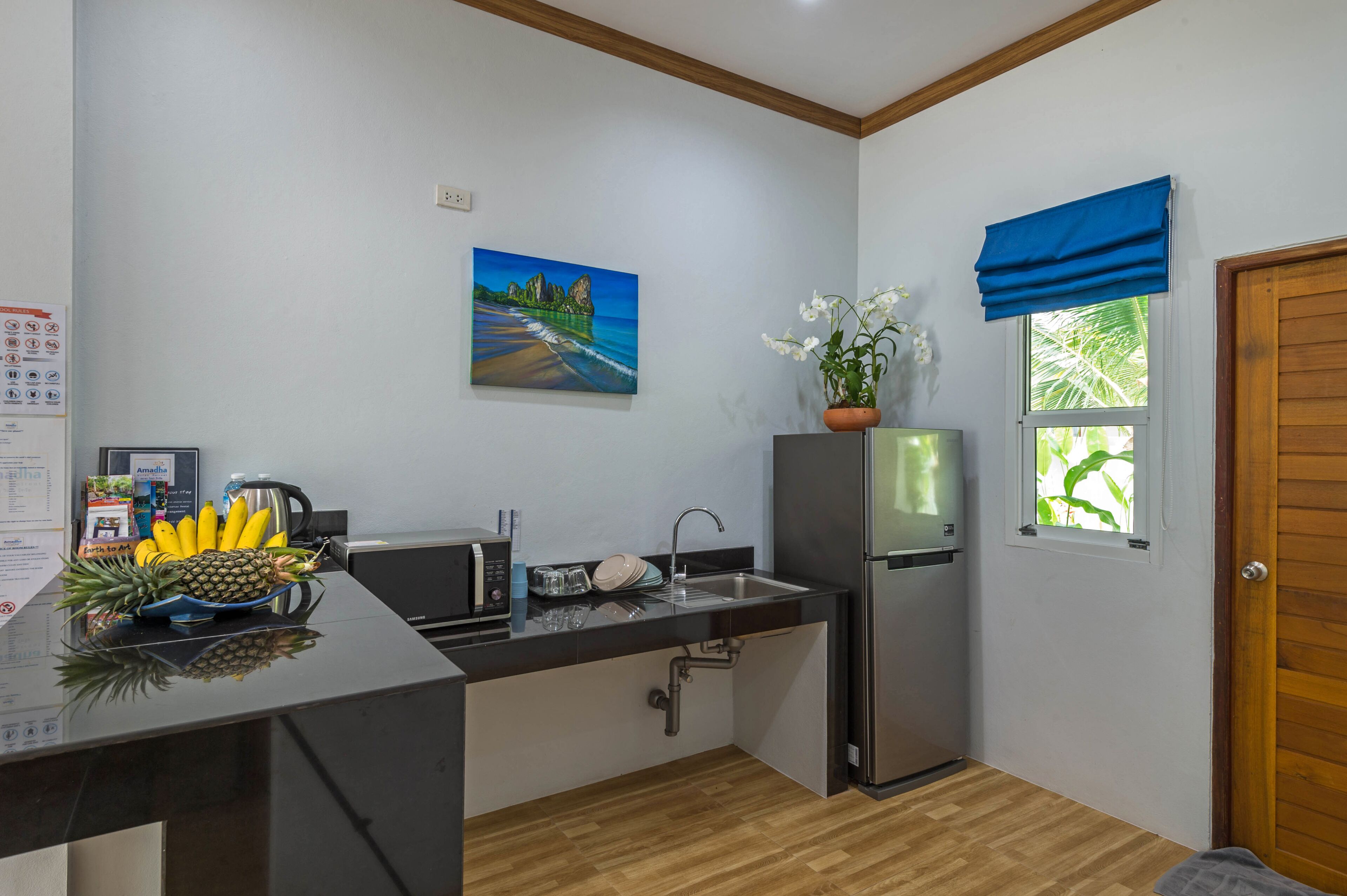 A compact kitchen with a sink, a refrigerator, and a window with a blue valance.