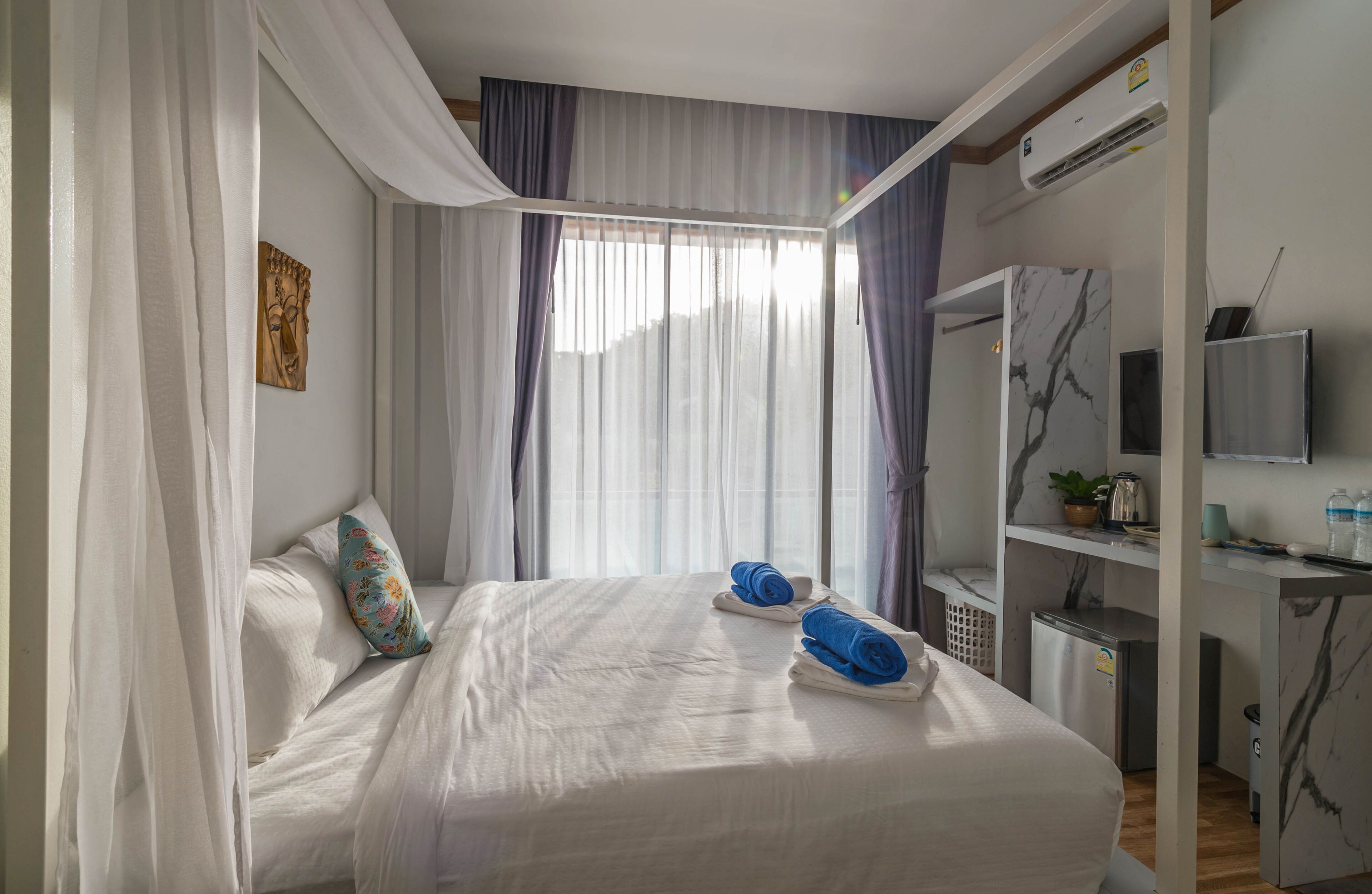 A hotel room with a bed, a TV, a desk, and a small refrigerator.