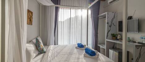 A hotel room with a bed, a TV, a desk, and a small refrigerator.
