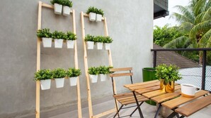 A wooden bench with a table, a chair, and a potted plant on a balcony. - Ariama Serviced Residence (Jakarta)