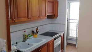 Une cuisine avec des meubles de rangement en bois, un plan de travail blanc, un évier et une cuisinière.