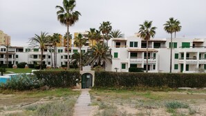 A pathway leading to a building with multiple balconies, surrounded by palm trees and a pool. - Deltamar 44 Solo Familias! (Xeraco Playa)