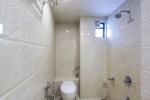 A bathroom with a shower, toilet, and a small window. - Hotel Marigold (Vadodara)