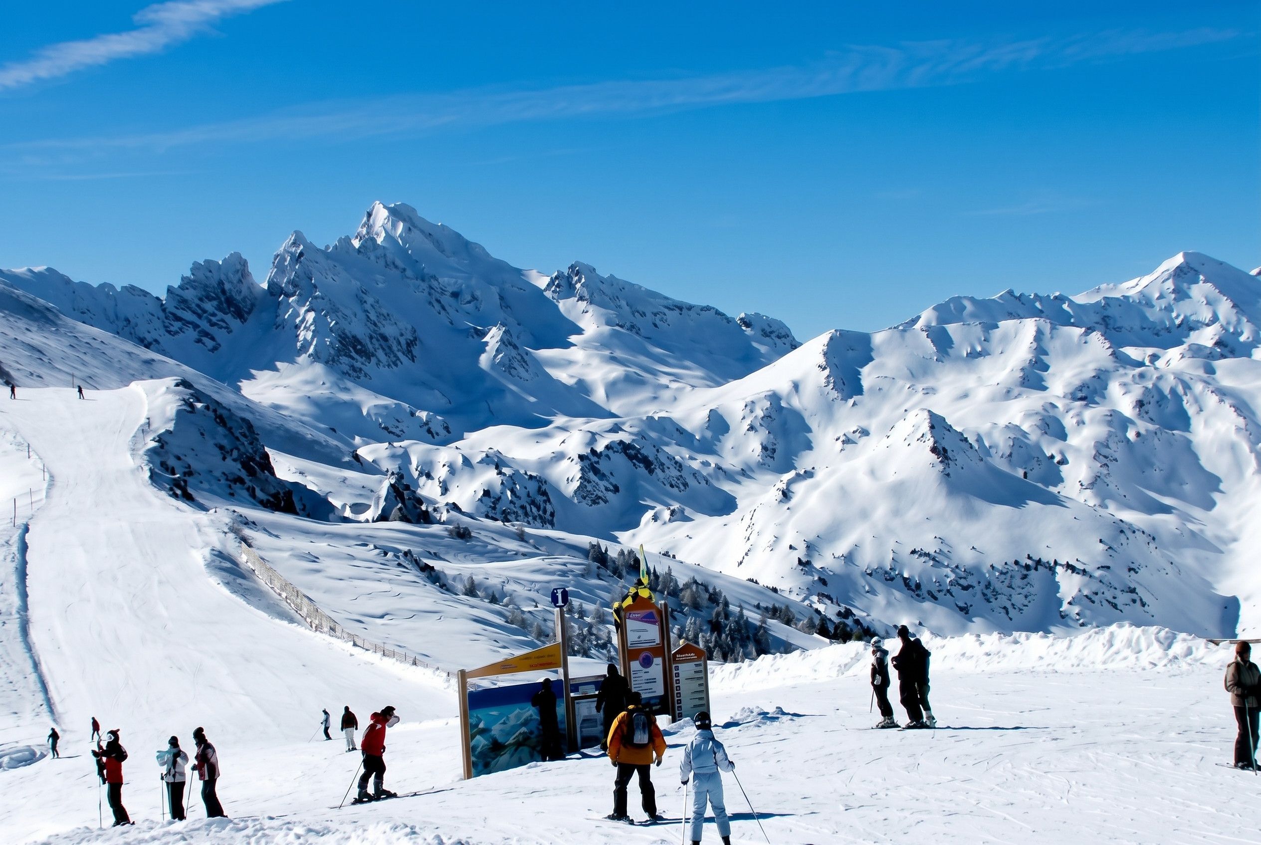 A snowy mountain landscape with skiers and a ski lift.