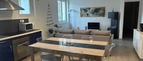 Un espace de vie compact comprenant une cuisine, un coin repas et un coin salon.