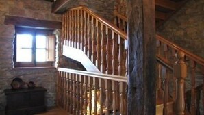 Eine Holztreppe mit Geländer, eine Steinmauer und ein Fenster mit Tageslicht.