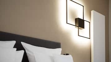 A hotel room with a modern headboard, a wall-mounted light fixture, and a large window.