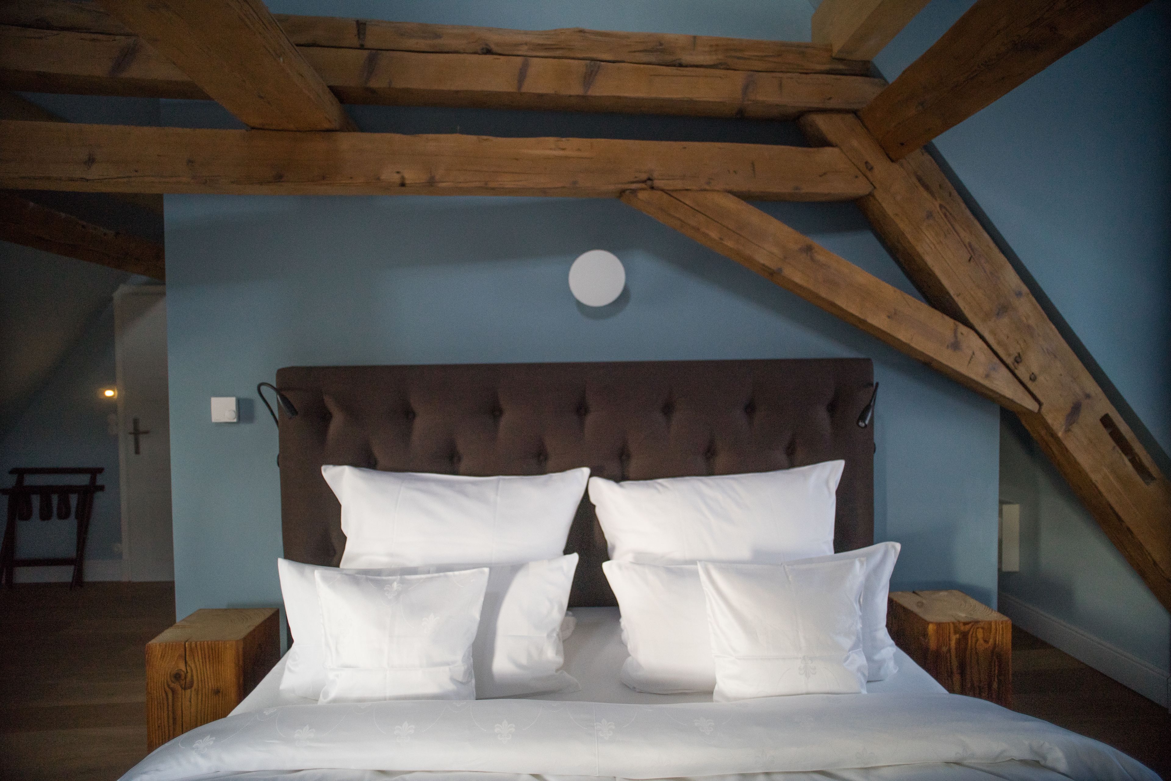 A bedroom with a large bed, wooden beams, and a cross on the wall.