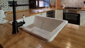 A kitchen with a wooden countertop, a white sink, a black faucet, and a window with a view of a brick wall. - "Casa Sira", a privilege for the senses (Villaviciosa)