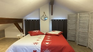 Een slaapkamer met een bed, een klein nachtkastje, een spiegel en een kast met verstelbare deuren.