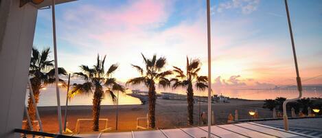 A terrace with a view of the beach and sunset.