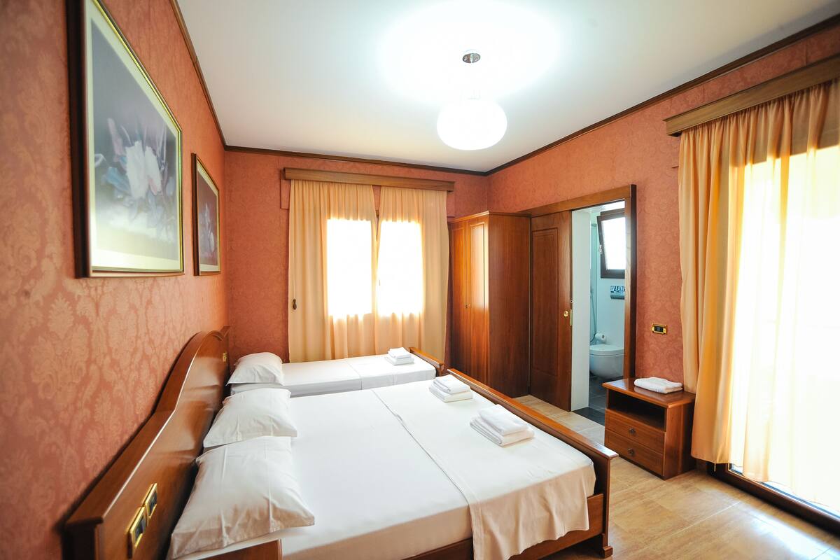A hotel room with two beds, a bathroom, and a large mirror.