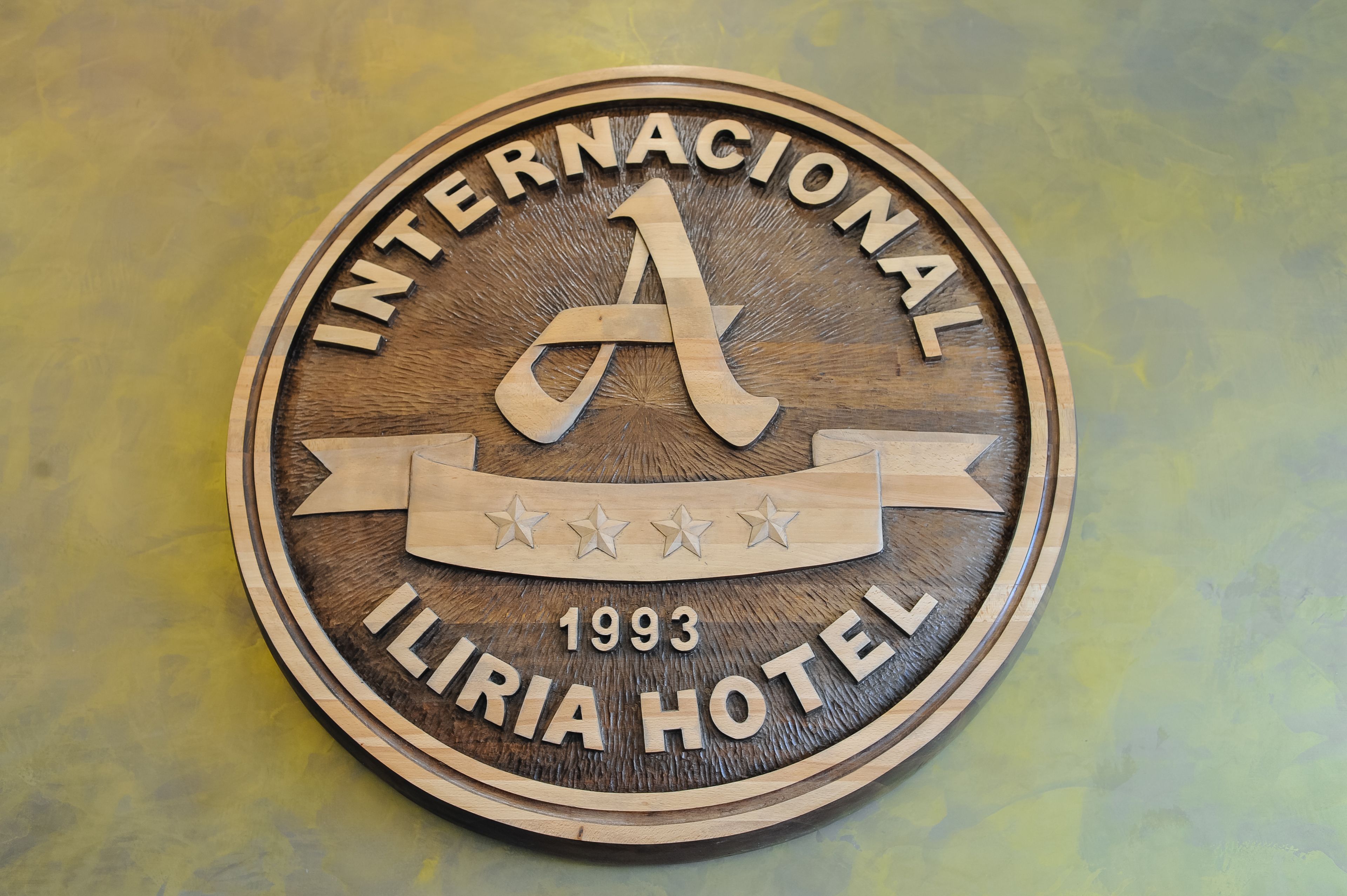 A wooden sign for the Internacional Iliria Hotel, featuring a large 'A' and the year 1993.