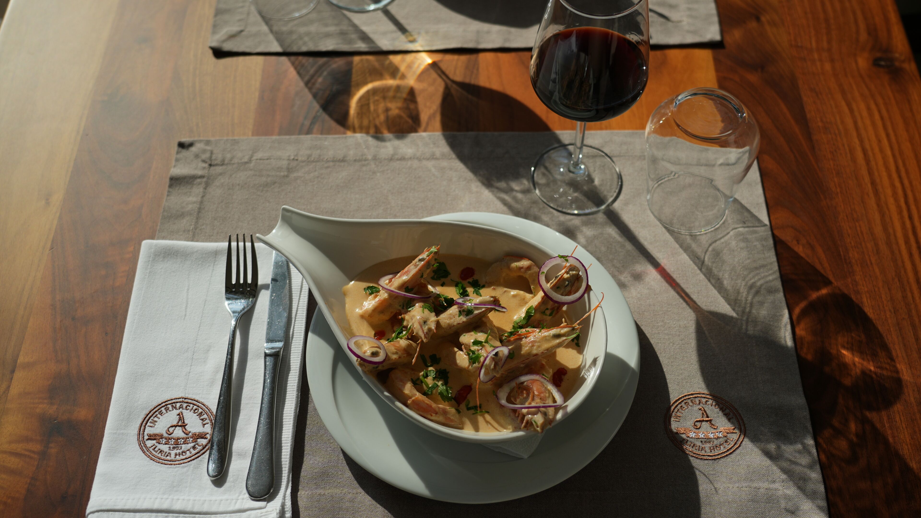 Une table avec une assiette de fruits de mer, un verre de vin rouge et un verre d’eau.