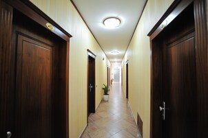 Un couloir avec des portes en bois, une plante en pot et un sol carrelé.