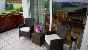 A balcony with wicker furniture, a glass door, and a view of the outdoors. - Like new EFH for 6 pers. with garage in close proximity to Sorpesee (Langscheid)