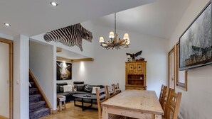 Amplia sala de estar con una mesa de comedor de madera, un sofá y una escalera que lleva a otro nivel.
