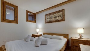 Un dormitorio con una cama de madera, dos mesitas de noche y una lámpara de pared.