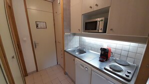 Une cuisine compacte équipée d’un four à micro-ondes, d’une machine à café et d’un lave-vaisselle.