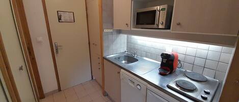 A compact kitchen with a microwave, coffee maker, and dishwasher.