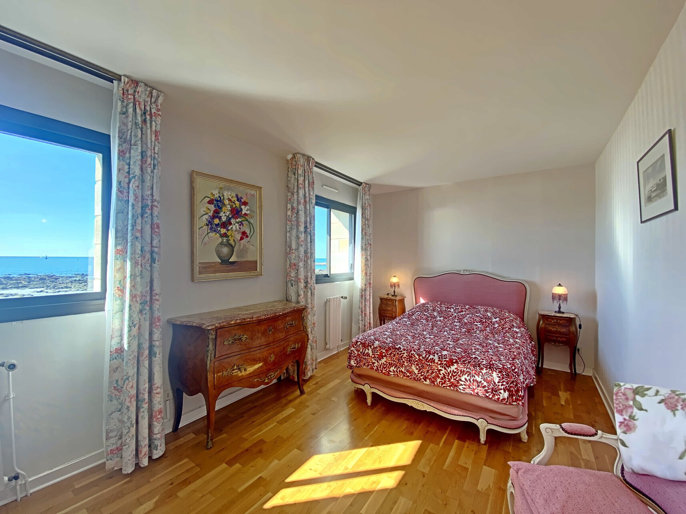 Ein Schlafzimmer mit Bett, Schminktisch und einem Blumenbild.