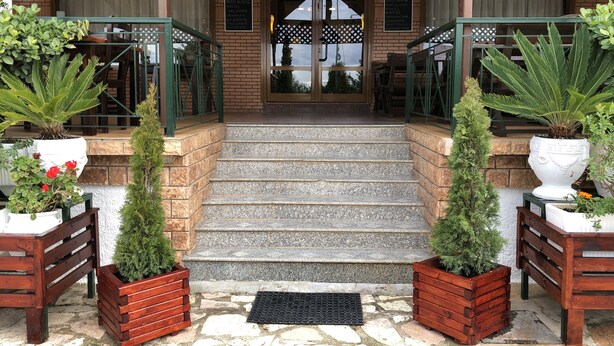 A brick building with a stone staircase leading to a wooden door. - Hotel Beer House (Sarandë)