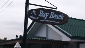 A sign for 'Bay Beach Kudawella' with a beach and palm tree design. - The Bay Beach (Tangalle)