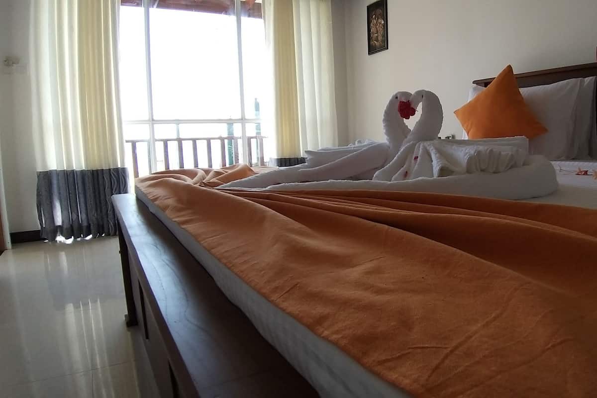 A hotel room with a bed, orange bedspread, two swan-shaped towels, and orange pillows.