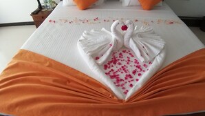 A neatly made bed with a swan towel design and orange and white bedding. - The Bay Beach (Tangalle)