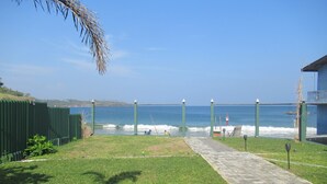 A paved pathway leading to a beach with a green fence and a view of the ocean. - The Bay Beach (Tangalle)