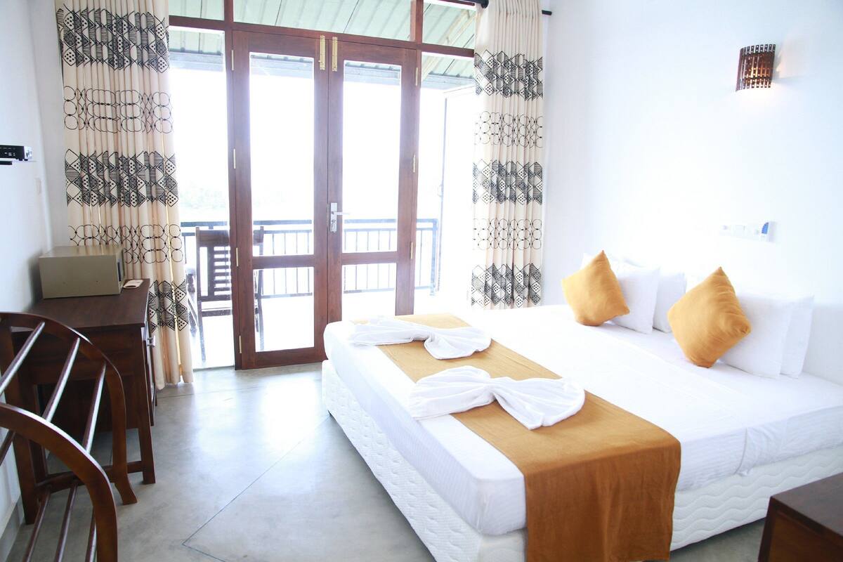 A hotel room with a bed, a desk, and a balcony.