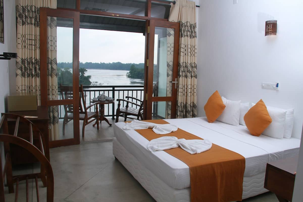 A hotel room with a bed, a desk, and a view of a river.