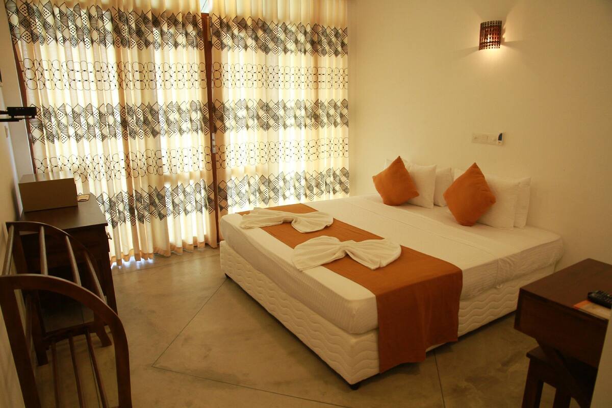 A hotel room with a bed, a desk, and a chair.