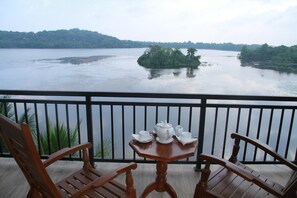 A wooden table with a tea set on a balcony overlooking a calm lake with a small island. - Sanu Lagoon Resort & Spa (Tangalle)