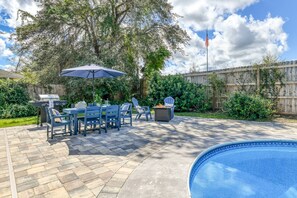 Un patio trasero con piscina, mobiliario de jardín y zona de barbacoa.