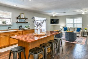 Une cuisine moderne avec un îlot central en bois, des tabourets de bar et un coin repas comprenant un canapé et des chaises.