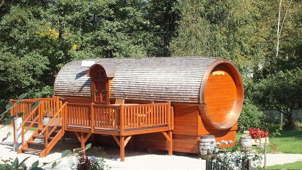 Un edificio con forma de barril de madera, con terraza y escaleras.