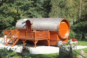 Un edificio con forma de barril de madera, con terraza y escaleras.