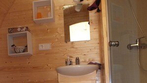 Baño de cabaña de madera con lavabo, espejo y ducha.