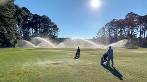 A golf course with a clear sky, trees, and people playing golf. - Driftwood 4 bedrooms, 3 bathrooms (Jekyll Island)