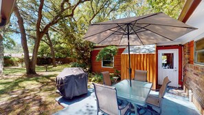 Een terras met een tafel, stoelen en een parasol.