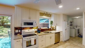 A kitchen with white cabinets, a microwave, a stove, a sink, and a dishwasher. - Driftwood 4 bedrooms, 3 bathrooms (Jekyll Island)