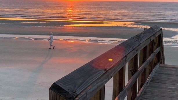 A wooden boardwalk leading to a beach with a sunset in the background. - Driftwood 4 bedrooms, 3 bathrooms (Jekyll Island)