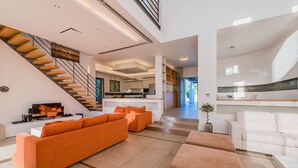 Un salon moderne avec un escalier, une cuisine et un coin repas.
