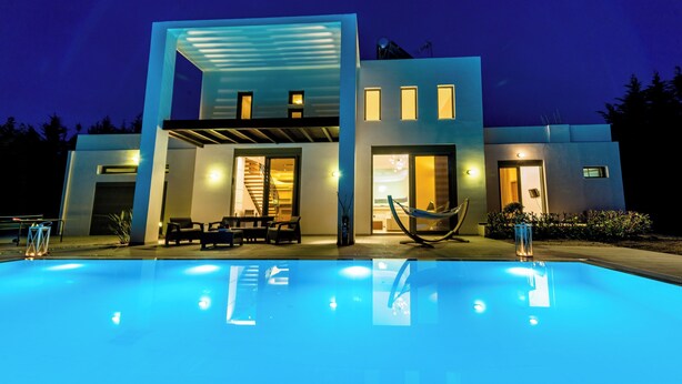 Une maison moderne dotée d’une piscine, de grandes fenêtres et d’un hamac.