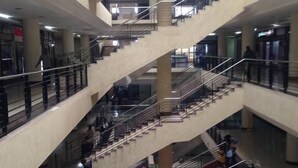 Un atrium à plusieurs niveaux, doté d’un escalier central reliant les différents étages, et entouré d’espaces ouverts et de colonnes.