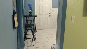 A hallway with a blue door, a white door, and a small table with a potted plant. - Kozy Bahamas Getaway (Nassau)