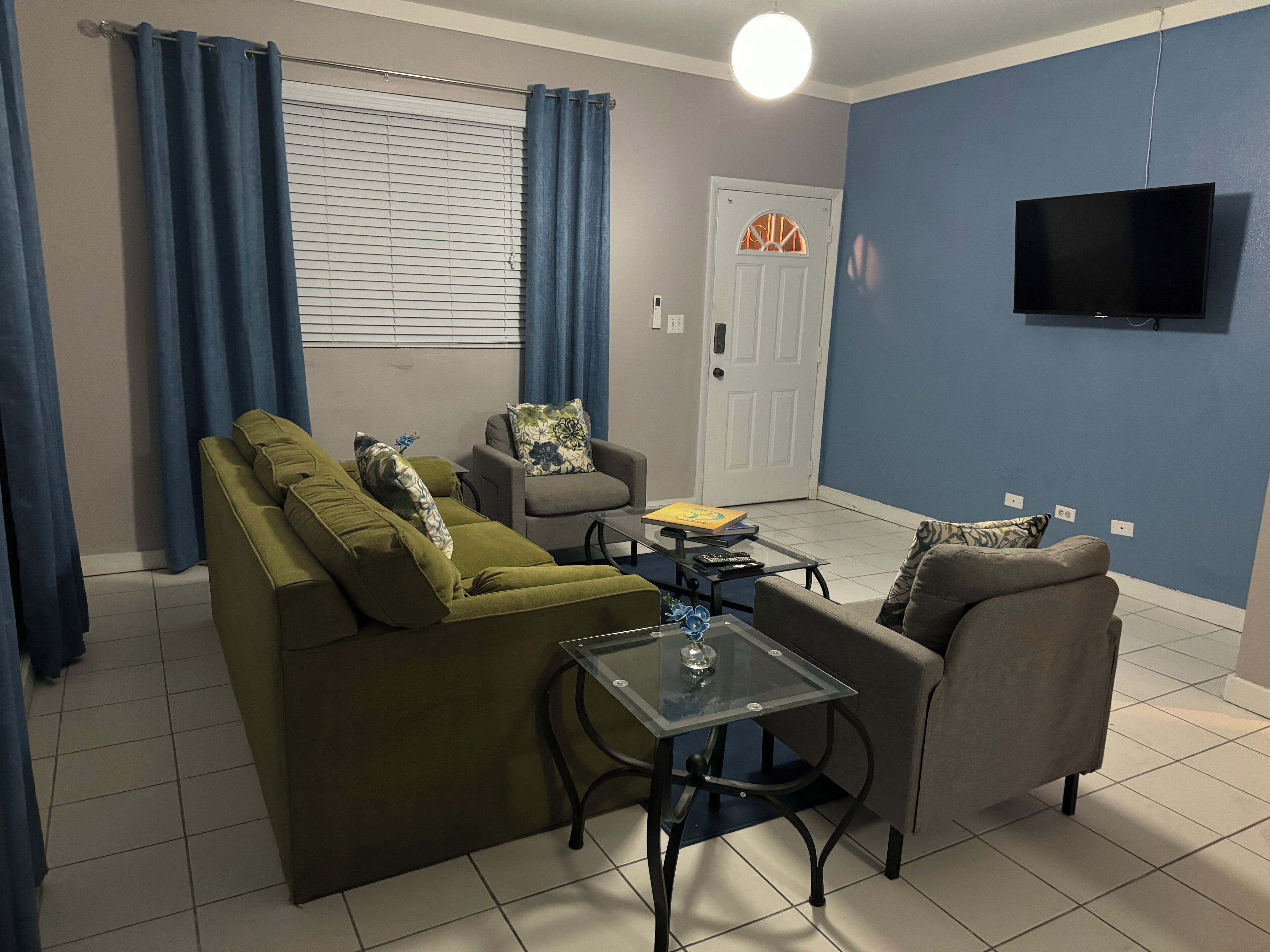Un salón con sofá, sillones, una mesa de centro y televisor.