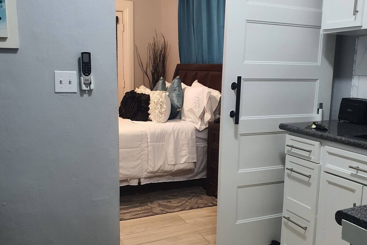 A room with a bed, a desk, and a sliding door leading to another room.
