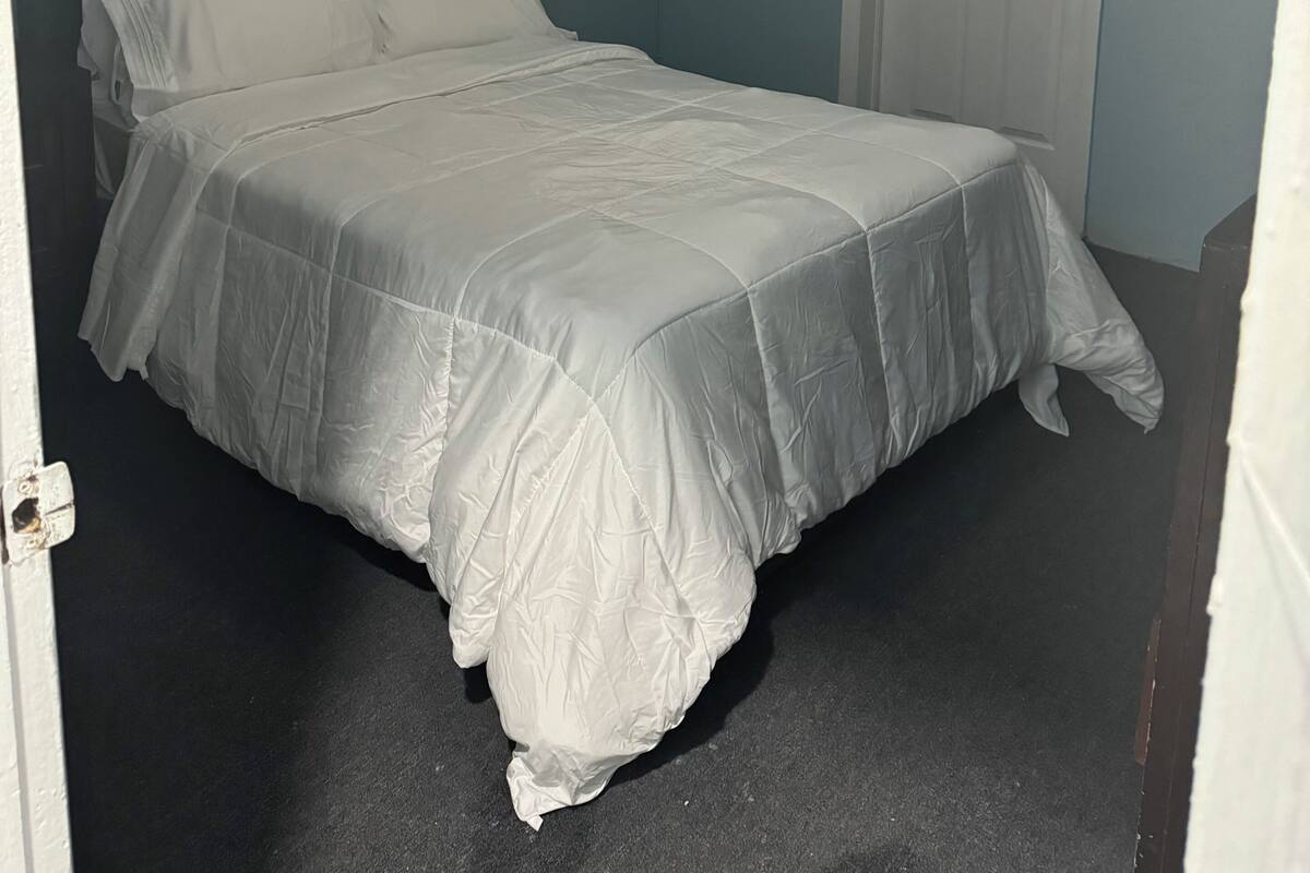 A bedroom with a bed, a ceiling fan, and a door.